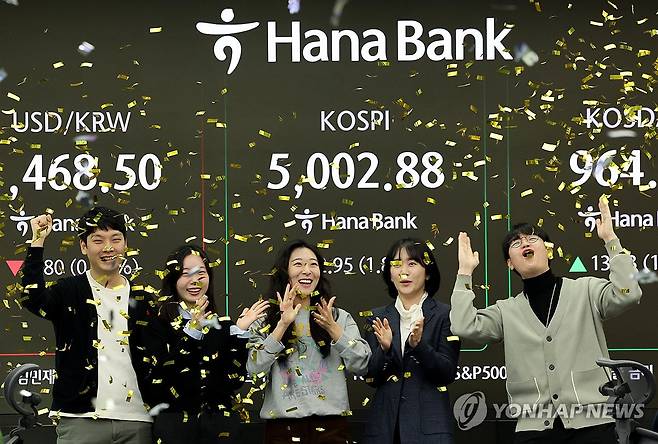 코스피, 장중 사상 첫 5,000선 돌파 (서울=연합뉴스) 이진욱 기자 =  코스피가 장중 5,000을 넘어선 가운데 22일 오전 서울 중구 하나은행 딜링룸에서 외환 딜러들이 세리머니를 펼치고 있다. 2026.1.22 cityboy@yna.co.kr