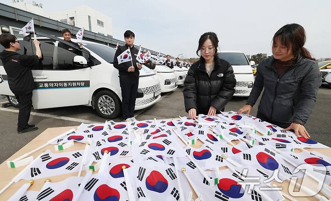 제107주년 3·1절을 사흘 앞둔 26일 경기 수원시 권선구 수원시교통약자지원센터 한아름콜에서 직원들이 3·1절을 맞아 교통약자지원차량에 부착할 태극기를 준비하고 있다. 2026.2.26 ⓒ 뉴스1 김영운 기자