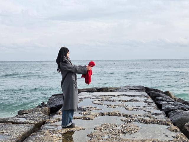 7일 중국인 관광객 리칭(20)이 드라마 '도깨비' 촬영지로 유명한 강원 강릉시 주문진 영진해변에서 빨간 목도리를 들고 있다. 강릉=나민서 기자