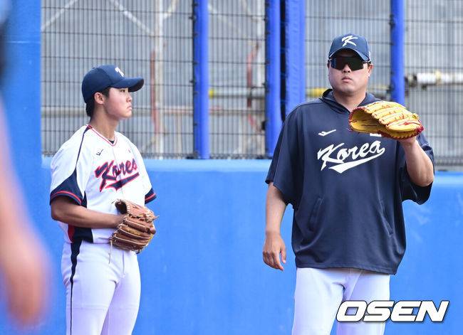 [OSEN=오키나와(일본), 최규한 기자] 2026 WBC(월드베이스볼클래식)를 준비하는 대한민국 야구 대표팀이 26일 일본 오키나와 가데나 야구장에서 프로야구 삼성 라이온즈와 연습경기를 펼쳤다. 야구 대표팀은 오키나와에서 국내 팀들과 6차례 연습경기를 치르며 전력을 끌어올릴 예정이다.4회말 공격 때 대표팀 류현진이 몸푸는 정우주 옆에서 파울 타구를 막아주고 있다. 2026.02.26 / dreamer@osen.co.kr