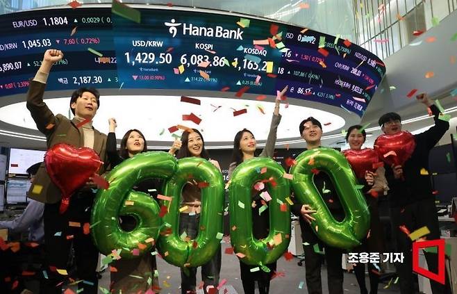 코스피가 사상 처음으로 6000선을 돌파하며 장을 마감한 지난 25일 서울 중구 하나은행 본점 딜링룸에서 직원들이 축하 세레머니를 하고 있다. 조용준 기자