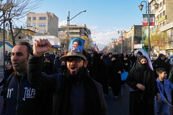 2026년 3월 1일 일요일 이란 테헤란에서, 미국과 이스라엘의 공습으로 이란 최고지도자 아야톨라 알리 하메네이의 사망이 확인된 뒤, 하메네이의 사진이 그려진 모자를 쓴 한 남성이 정부 지지자들과 함께 하메네이의 거주지를 향해 행진하고 있다. AP연합뉴스