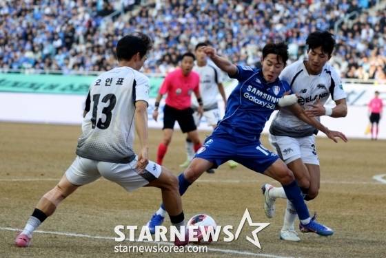 김성주(가운데)가 서울 이랜드 선수 두 명에 둘러싸여 있다./사진=강영조 선임기자