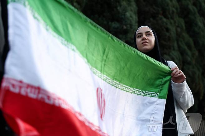 이란 국기를 든 여성. ⓒ 로이터=뉴스1
