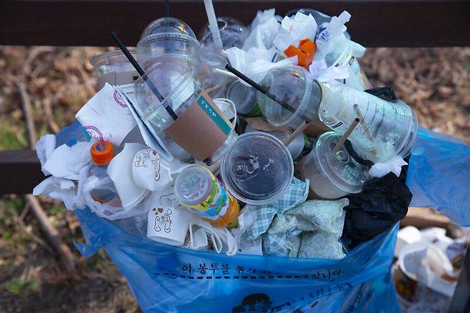 쓰레기 더미 위로 플라스틱으로 만든 일회용 컵들이 쌓여 있다. 클립아트코리아