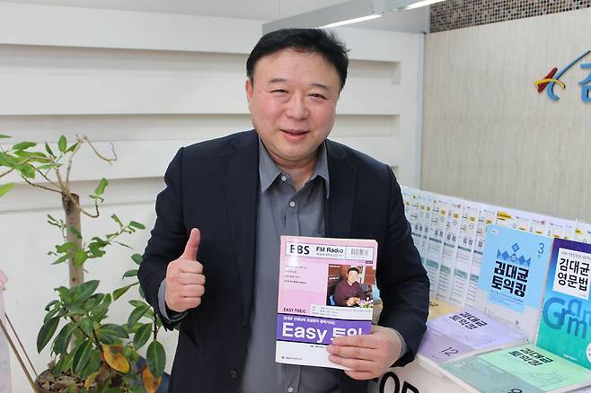 지난달 25일 서울 강남구 토익 학원에서 김대균 강사가 교재를 들어보이고 있다. 2003년 EBS 라디오 토익 강의를 시작할 당시 제작한 책이다. 강의실 벽은 토익 만점 증명서로 가득 차 있다. 김민상 기자
