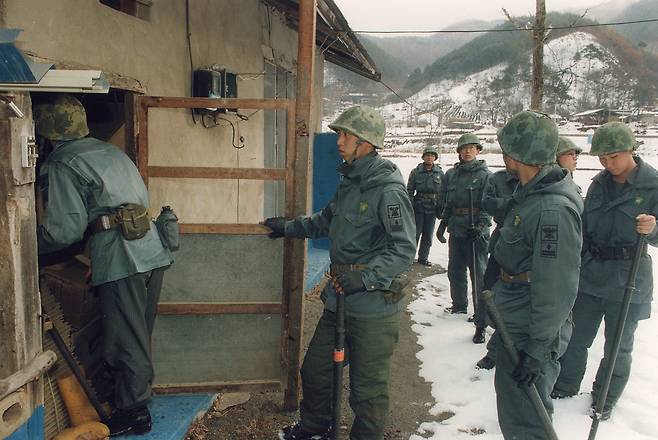Police officers search for Shin Chang-won, who had been on the lam for a year in a rural town in South Chungcheong in January 1998. [JOONGANG ILBO]