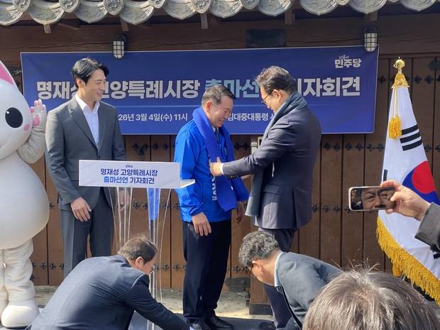 4일 오전 고 김대중 전 대통령 사저 앞에서 송영길 전 민주당 대표가 명재성 고양시장 예비후보(가운데)에게 파란 목도리를 메어주고 있다. 사진 제공=명재성 예비후보 캠프