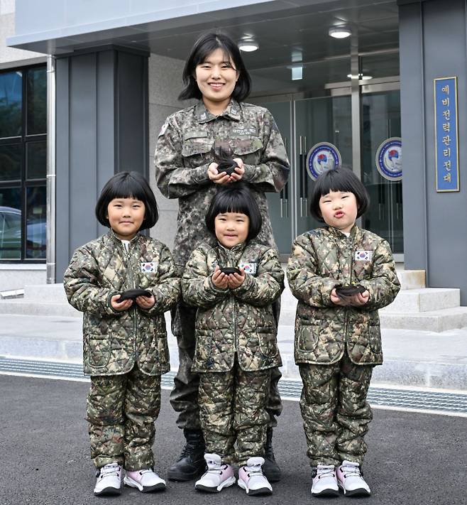 해군 제8전투훈련단 소속 이은주 상사와 세쌍둥이 딸(왼쪽부터 장은진(첫째), 장소진(셋째), 장유진(둘째))들이 소아암 아동 돕기를 위해 자른 각 25cm 길이의 머리카락을 손에 들고 기념사진을 촬영하고 있다./사진=해군8전단