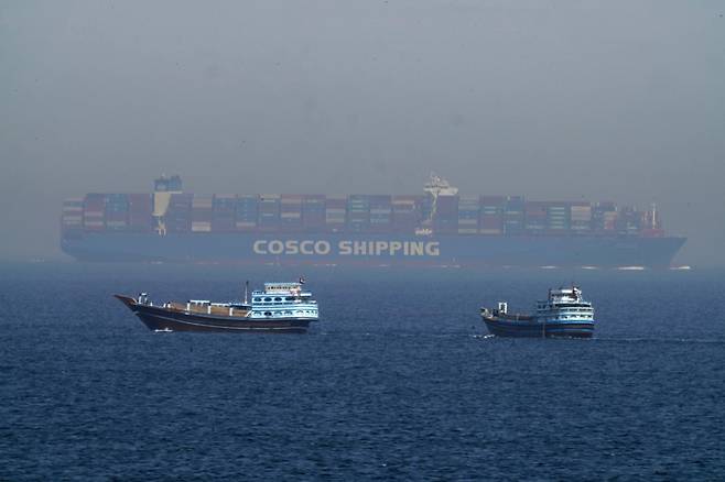 FILE - Two traditional dhows sail by a large container ship in the Strait of Hormuz, May 19, 2023. (AP Photo/Jon Gambrell, File)