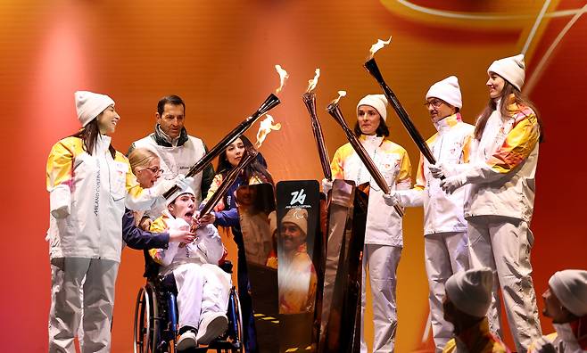 지난 3일 이탈리아 코르티나 담페초에서 열린 2026 밀라노·코르티나담페초 동계 패럴림픽 성화 봉송 및 합화식에서 성화 주자들이 성화를 하나로 합치고 있다. 신화통신