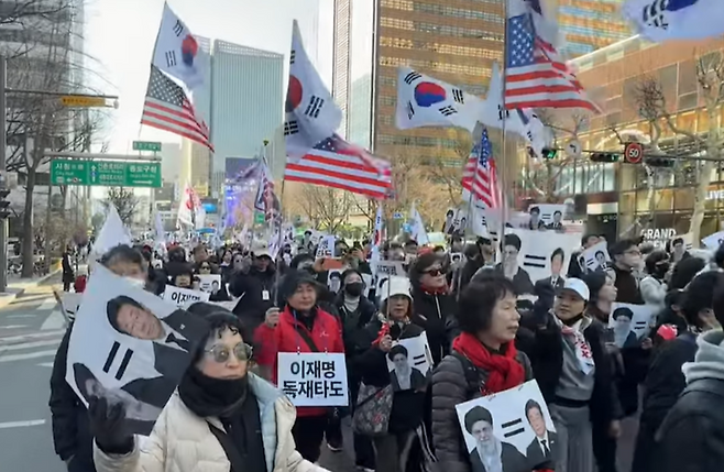 극우성향 단체 자유대학 회원들이 지난 7일 서울 종로구 일대에서 이재명 대통령·아야톨라 알리 하메네이 이란 최고지도자의 얼굴이 그려진 손팻말을 들고 행진하고 있다. 자유대학 유튜브 갈무리