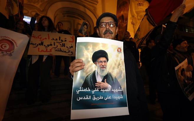 튀니지 튀니스에서 7일(현지시간) 열린 집회에서 한 참석자가 미국과 이스라엘의 공격으로 사망한 이란 최고지도자 아야톨라 알리 하메네이의 사진을 들고 있다. 연합뉴스
