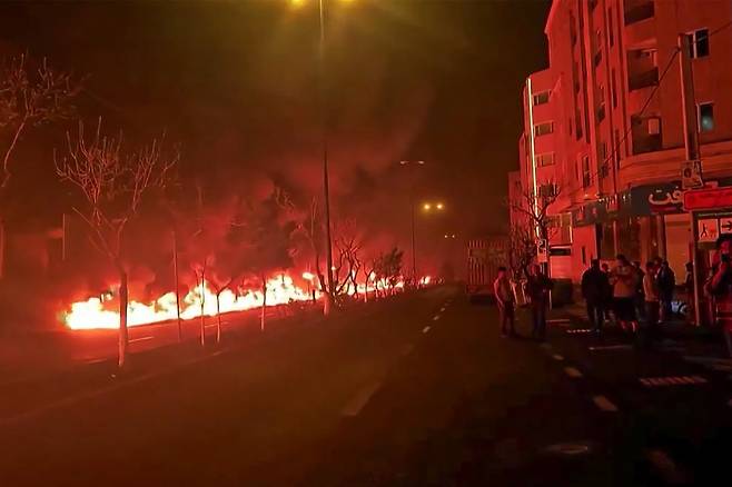 7일 밤과 8일 새벽 공습으로 이란 테헤란 석유 저장 시설이 폭발하면서 거리가 화염에 휩싸인 모습./ AFP 연합뉴스