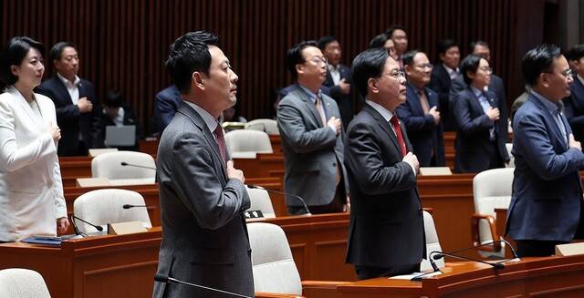 장동혁 대표와 송언석 원내대표를 비롯한 국민의힘 의원들이 9일 국회에서 열린 긴급 의원총회에서 국기에 경례하고 있다. 연합뉴스