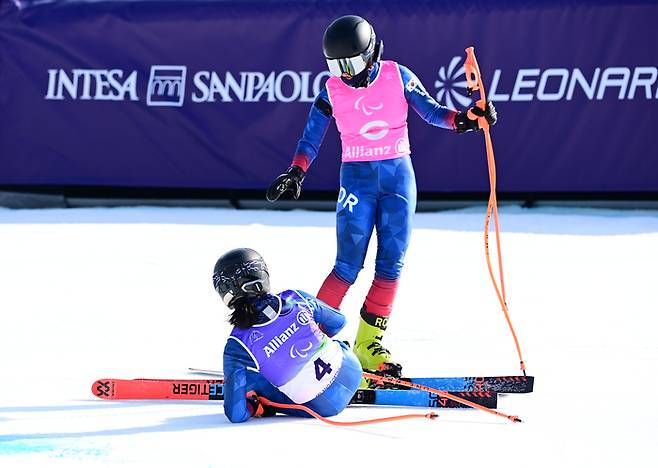 최사라(아래)가 이탈리아 코르티나 토파네 알파인스키 센터에서 열린 2026 밀라노·코르티나 동계패럴림픽 알파인스키 여자 슈퍼대회전 레이스를 마친 후 넘어지지 어은미 가이드가 손을 내밀고 있다. 사진 | 대한장애인체육회