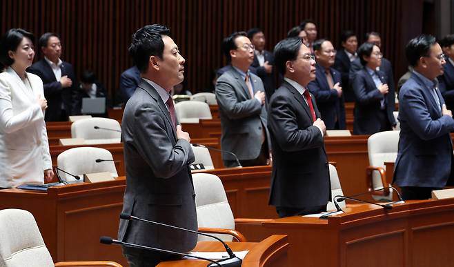 장동혁 대표와 송언석 원내대표를 비롯한 국민의힘 의원들이 지난 9일 국회에서 열린 긴급 의원총회에서 국기에 경례하고 있다. 연합뉴스