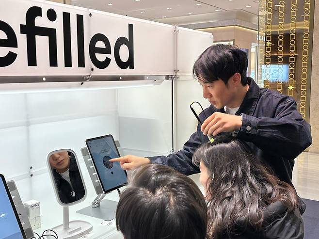 콘스탄트 정근식 대표가 리필드 AI 두피 스캐닝 기술을 현대백화점 판교점에서 소비자들에게 선보이고 있다. <제공: 콘스탄트>