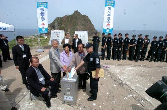 헌정 사상 처음으로 독도에 부재자투표소가 설치돼 2006년 5월 25일 투표가 이뤄졌다. 독도 주민 김성도.김신열 부부, 서기종 독도의용수비대동지회장이 함께 투표지를 넣고 있다. 중앙포토