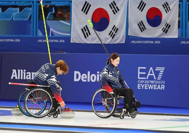 Korea’s Lee Yong-seok, left, and Baek Hye-jin pause to confer after the sixth end during the wheelchair curling mixed doubles semifinal against the United States at the 2026 Milan-Cortina Winter Paralympics at the Cortina Curling Olympic Stadium in Cortina, Italy, on March 10. [YONHAP]