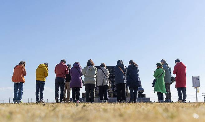 2011년 동일본대지진 15주년인 11일 일본 후쿠시마현 나미에마을 주민들이 희생자 추모비 앞에서 기도하고 있다. 후쿠시마 제1원전에서 약 8㎞ 떨어진 나미에마을은 당시 거대 쓰나미로 주민 1만9000여명이 죽거나 실종됐고, 방사능 유출로 마을 전체가 피난길에 올라야 했다. 나미에=AFP연합뉴스