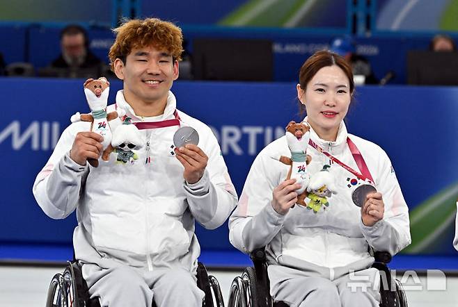 [코르티나담페초=뉴시스] 사진공동취재단 = 휠체어컬링 백혜진(오른쪽)과 이용석이 11일(현지 시간) 이탈리아 코르티나담페초 컬링 올림픽 스타디움에서 열린  2026 밀라노 코르티나 패럴림픽 휠체어컬링 믹스더블에서 은메달을 차지한 뒤 메달을 들어보이고 있다. 2026.03.12. photo@newsis.com