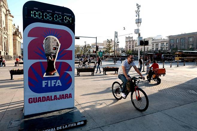 한 남성이 지난 2일 멕시코 할리스코주 과달라하라에서 자전거를 타고 2026 국제축구연맹(FIFA) 월드컵 개막 100일을 알리는 카운트다운 시계 앞을 지나가고 있다. AFP