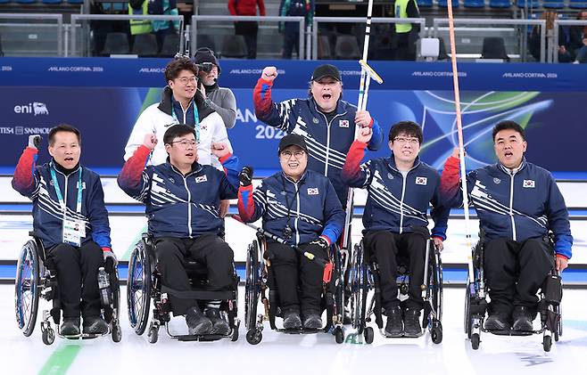 휠체어컬링 혼성팀이 12일(현지시간) 이탈리아 코르티나 컬링 올림픽 스타디움에서 열린 2026 밀라노·코르티나 동계패럴림픽 휠체어컬링 혼성팀 예선 최종전 이탈리아와 경기에서 승리하며 준결승 진출에 성공했다. 경기 후 이충용 코치-임성민 감독(뒷줄 왼쪽부터), 양희태-이현출-방민자-남봉광-차진호(아랫줄 왼쪽부터)가 파이팅을 외치고 있다. 사진 | 대한장애인체육회