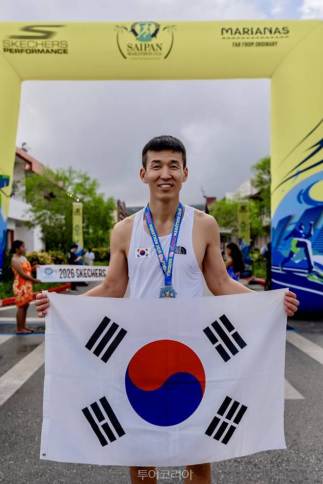 가수 션이 '사이판 마라톤 2026' 현장에서 태극기를 들고 포즈를 취하고 있다./ 사진- 마리아나관광청
