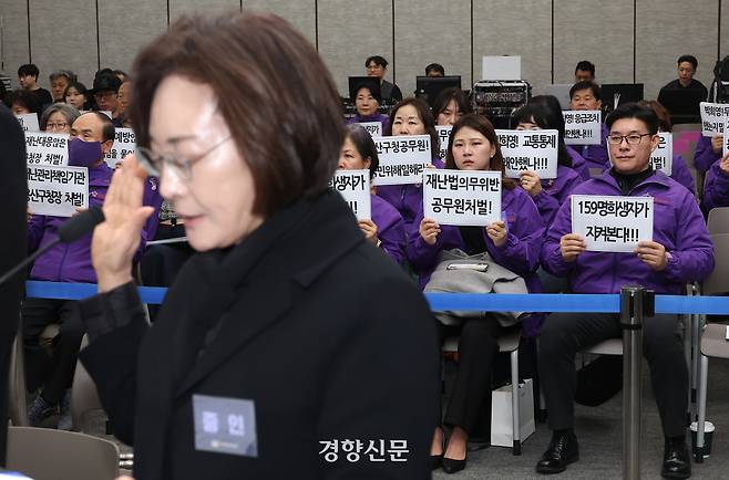 13일 서울 중구 은행회관에서 열린 10·29 이태원참사 진상규명 청문회에서 박희영 용산구청장이 증인선서를 하는 가운데 유가족들이 책임자 처벌을 촉구하는 손팻말을 들고 있다.