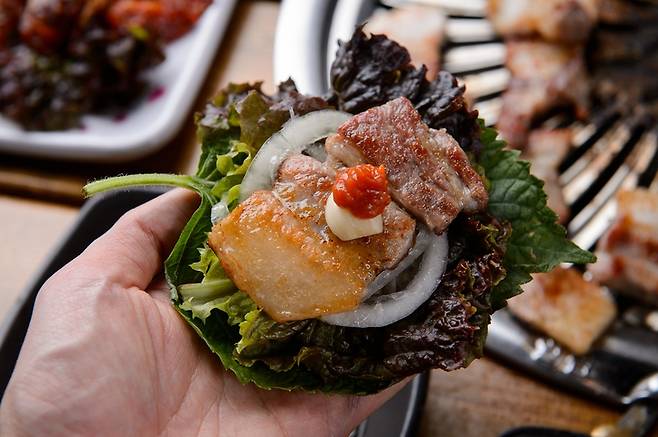 삽겹살을 상추에 싸고 있다. 밥·빵·떡·면 등 탄수화물 섭취를 줄이는 대신 질 좋은 지방이 풍부한 삼겹살, 소고기 등 육류와 연어 등 생선, 올리브유 버터 치즈 견과류 달걀 등의 섭취를 늘리는 식단을 '저탄고지 식단'(케토제닉 식단)이라고 한다. 이 식단이 뇌전증(간질) 발작 횟수를 줄여준다는 연구 결과가 나왔다. 게다가 뇌의 에너지 시스템 강화, 염증 감소, 신경 세포 보호 등 각종 치료 효과를 낸다는 것이다. 한국 뇌전증 환자는 36만~37만명으로 추산된다. 사진=게티이미지뱅크