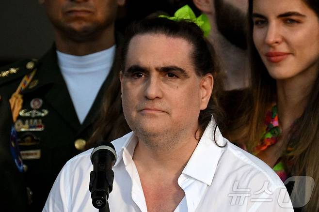 콜롬비아 출신 사업가 알렉스 사브가 2023년 12월 20일 카라카스 미라플로레스 대통령궁에서 아내 카밀라 파브리(오른쪽)와 함께 발언하고 있다. 2023.12.20.ⓒ AFP=뉴스1