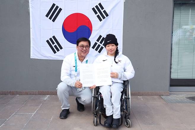 김윤지가 13일(현지시간) 이탈리아 테세로 크로스컨트리 스타디움에서 열린 2026 밀라노·코르티나 동계패럴림픽 여자 바이애슬론 스프린트 추적 좌식 은메달을 따낸 후 문화체육관광부 최휘영 장관을 만나 이재명 대통령 축전을 받고 있다. 사진 | 대한장애인체육회