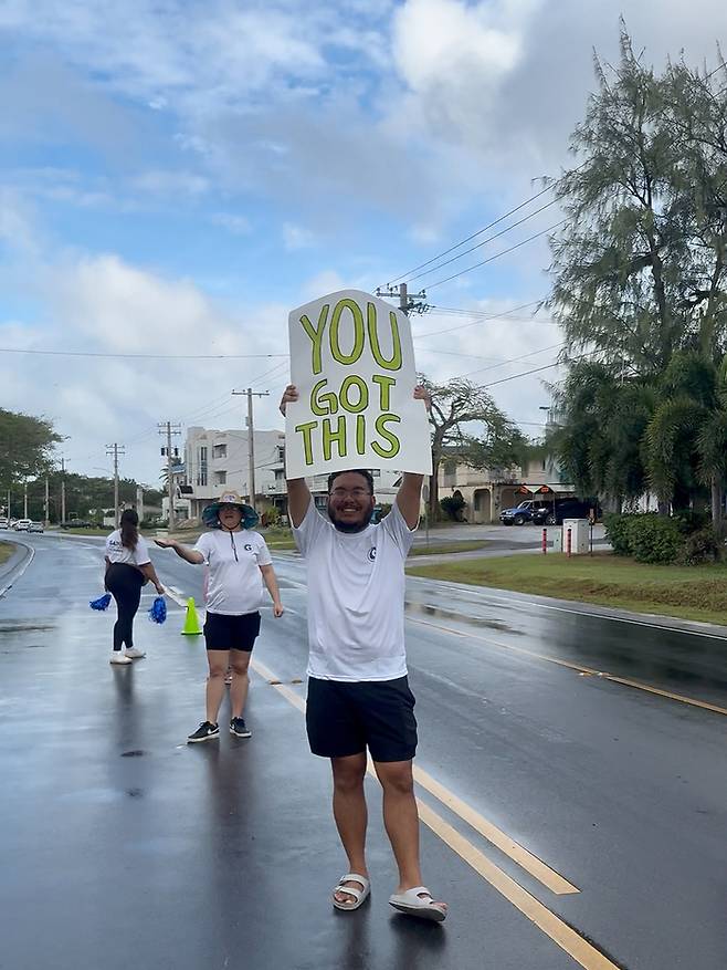 ‘할 수 있어(You got this)’라고 적힌 플래카드를 들고 마라톤 참가자를 응원하는 사이판 주민/사진=김지은 여행+ 기자