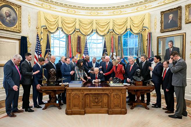 지난 5일(현지 시간) 미국 백악관에서 빨간색 옷을 입은 폴라 화이트 신앙사무국장 등 개신교 지도자들이 도널드 트럼프 미 대통령 어깨에 손을 얹고 대이란 전쟁 관련 기도를 하고 있다. 백악관 홈페이지