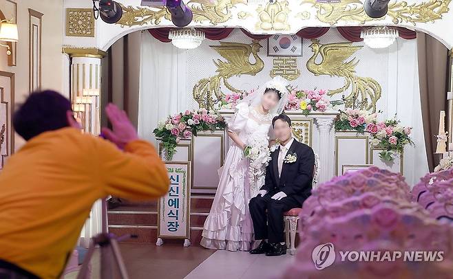 마산 신신예식장 레트로 결혼사진 (창원=연합뉴스) 김동민 기자 = 신신예식장 백남문 대표가 지난 11일 경남 창원시 마산합포구 신신예식장에서 예비 신혼부부의 결혼사진을 촬영하고 있다.
이곳은 고 백낙삼 전 대표가 1967년부터 55년간 예식장을 무료로 운영하며 1만4천여 쌍의 부부를 맺어준 뜻깊은 장소로 최근에는 '레트로 결혼사진' 명소로 인기를 끈다. 2026.3.14 image@yna.co.kr