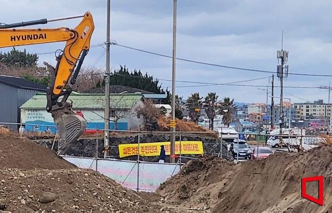 제주시 이호동의 한 건축 공사 현장. 마을 측이 '해안사구 보존'을 주장하며 내건 현수막과 함께 중장비가 멈춰 서 있다. 정작 마을에서 추천한 중장비 기사가 이 사구 모래를 대량 반출했다는 주장이 나와 논란이 일고 있다. 박창원 기자.