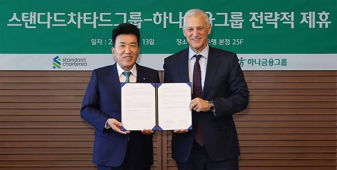 함영주 하나금융그룹 회장(왼쪽)과 빌 윈터스 스탠다드차타드그룹 회장이 지난 13일 서울 중구 하나은행 본점에서 글로벌 비즈니스 및 디지털 자산 협력을 위한 업무협약을 체결한 뒤 기념촬영을 하고 있다. 하나금융그룹 제공