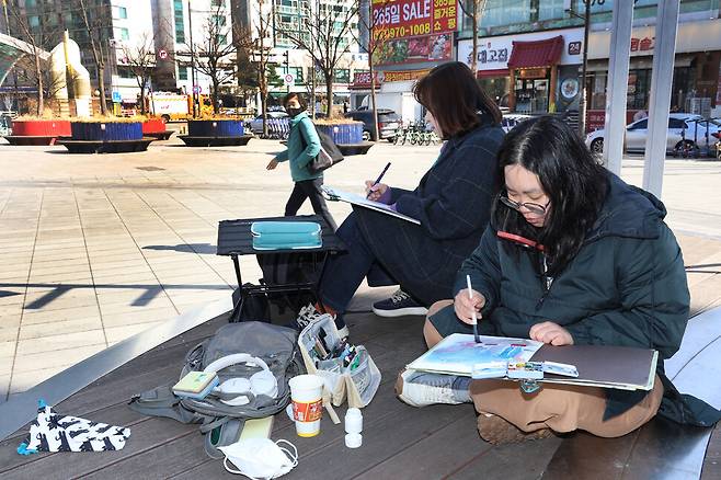 초(활동명·오른쪽)와 정상례씨가 화정역 광장에서 주변 풍경을 스케치하고 있다.