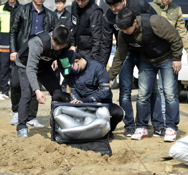 20대 동거녀를 살해 후 암매장한 피의자 이씨가 경기도 광명시의 한 도로변 공터에서 진행된 현장검증에서 범행을 재연하고 있다. 뉴스1