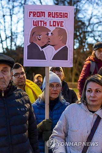 우크라이나전 발발 4주년 제네바 시위 (제네바 EPA=연합뉴스) 2026년 2월 24일 스위스 제네바의 유엔 유럽본부 청사 앞 광장에서 한 여성이 도널드 트럼프 미국 대통령과 블라디미르 푸틴 러시아 대통령의 얼굴과 함께 "러시아로부터 사랑을 보냅니다"라는 문구가 새겨진 플래카드를 들고 있다. (EPA/SALVATORE DI NOLFI) 2026.3.15.