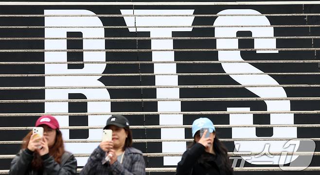 서울 종로구 세종문화회관 계단에 마련된 방탄소년단(BTS)의 컴백 라이브 공연 홍보물 앞에서 외국인 관광객이 기념촬영을 하고 있다. 약 3년 9개월 만에 컴백하는 방탄소년단(BTS)의 공연은 오는 21일 오후 8시 광화문광장에서 ‘BTS 컴백 라이브: 아리랑(ARIRANG)’이라는 타이틀로 개최된다. 2026.3.15 ⓒ 뉴스1 김명섭 기자