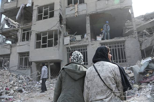 12일(현지시간) 이란 수도 테헤란의 폐허 속에서 주민들이 폭격에 손상된 건물을 뒤져 생필품을 찾고 있다. 2026.3.12 ⓒ 신화=뉴스1