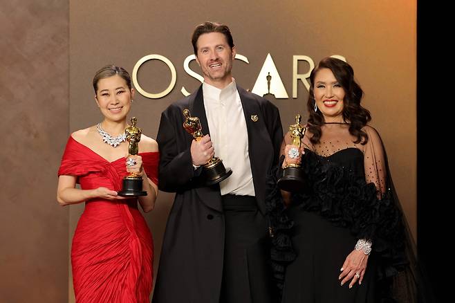 (왼쪽부터) 영화 ‘케이팝 데몬 헌터스’의 매기 강 감독과 크리스 아펠한스 감독, 제작자 미셸 웡이 15일(현지시간) 미국 캘리포니아 돌비 극장 할리우드 돌비 극장에서 열린 제98회 아카데미 시상식에서 장편 애니메이션상을 수상한 후 포즈를 취하고 있다. [AFP]