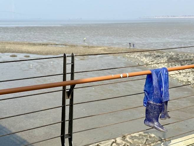 ▲&nbsp;17일 송도갯벌 인근 수변공원 난간에 어민의 작업복과 장화가 걸려 있다.
