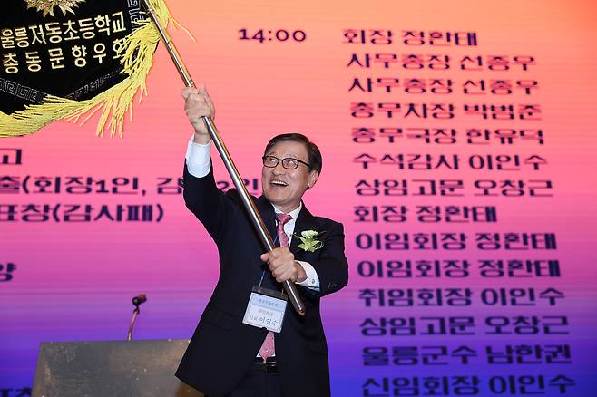 이인수 신임 울릉 저동초 총동문향우회장이 14일 대구 그랜드관광호텔에서 열린 취임식에서 정환태 이임 회장으로부터 전달받은 회기를 힘차게 흔들고 있다. /총동문향우회 제공