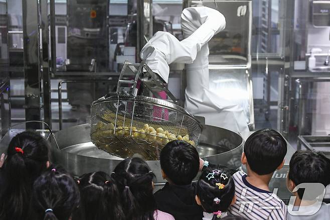 18일 경기 수원시 장안구 대평초등학교 내 위치한 거점형 학교급식 튀김 지원실에서 1학년 학생들이 튀김 조리 로봇이 직접 가동되는 현장을 보고 있다. (공동취재) 2026.3.18 ⓒ 뉴스1 김영운 기자