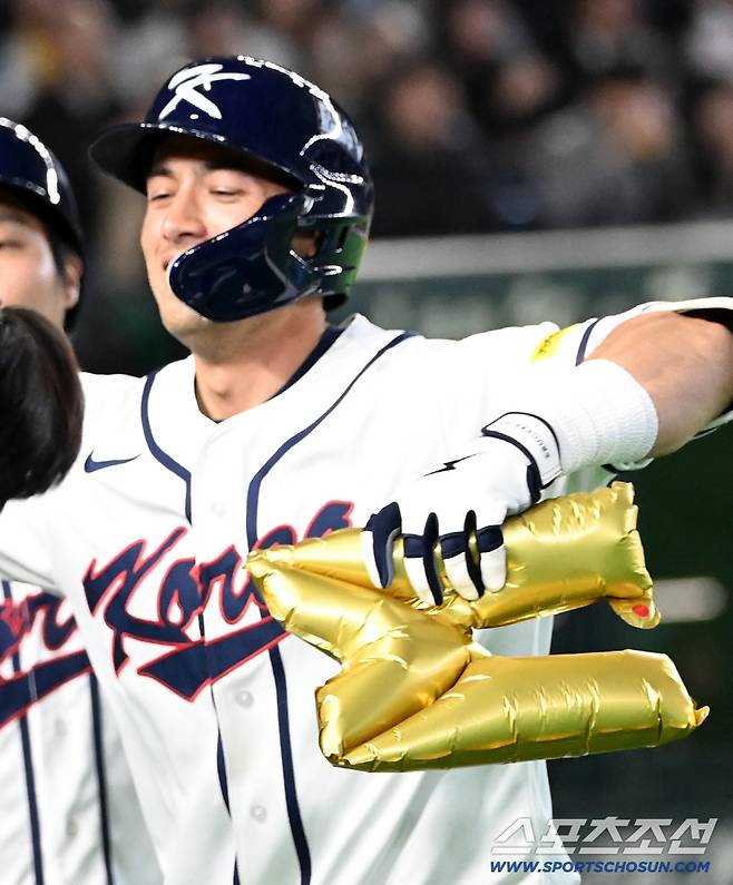 위트컴의 손에 들려진 금빛의 영롱한 M자 풍선!