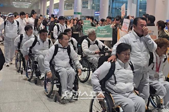 17일 귀국하는 패럴림픽 선수단 사이, 휠체어컬링 선수단 맨 앞에서 함께 행진하며 눈물을 흘리는 윤경선 대한장애인컬링협회장(오른쪽에서 두 번째). 인천공항=윤승재 기자&nbsp;