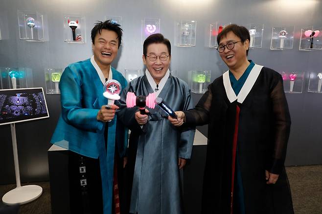 이재명 대통령이 지난해 10월 1일 경기도 고양시 킨텍스에서 열린 대중문화교류위원회 출범식에 앞서 박진영 공동위원장과 K컬처굿즈를 관람하며 블랙핑크 응원봉을 점등하고 있다. 사진=대통령실사진기자단